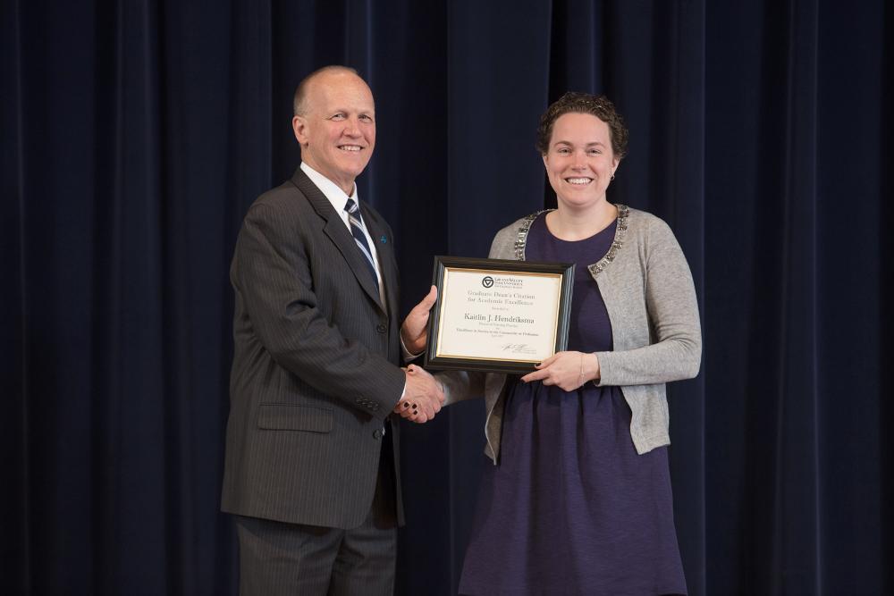 Doctor Potteiger posing for a photo with an award recipient in a grey sweater and purple dress